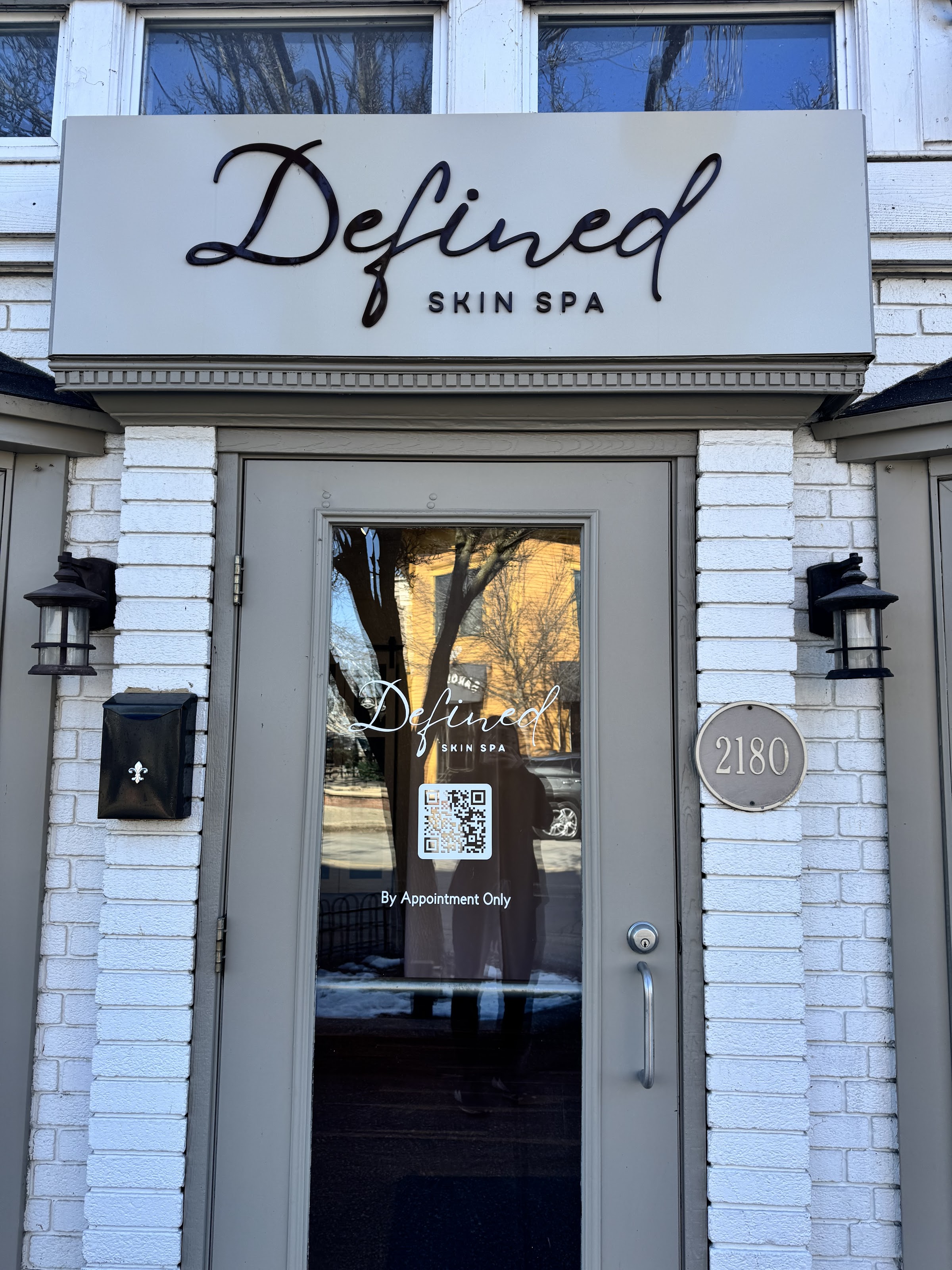 The Defined Skin Spa front door at 2180 Wealthy St SE — the cursive sign, the 2180 address plate and the By Appointment Only decal